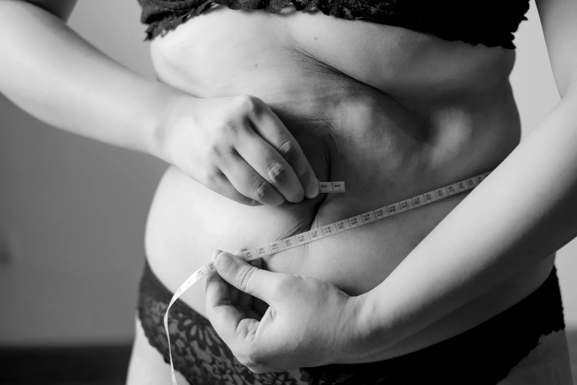 Personne mesurant son tour de taille, symbolisant les progrès réalisés avec l'aide de l'hypnose pour maigrir.